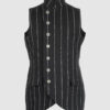 The long, fitted vest features a stand collar, a welt breast pocket, and pockets with pointed flaps.