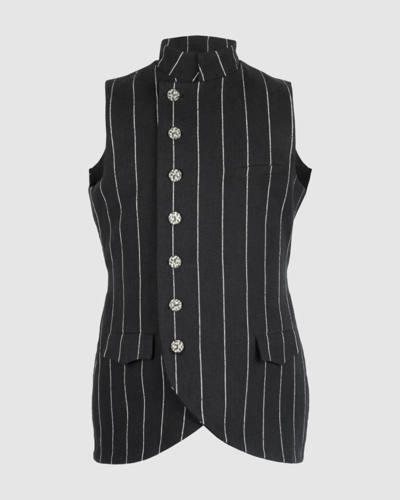 The long, fitted vest features a stand collar, a welt breast pocket, and pockets with pointed flaps.