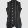 The long, fitted vest features a stand collar, a welt breast pocket, and pockets with pointed flaps.