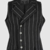 The long, fitted vest features a stand collar, a welt breast pocket, and pockets with pointed flaps.