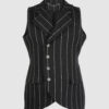 The long, fitted vest features a stand collar, a welt breast pocket, and pockets with pointed flaps.