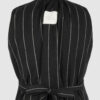 The long, fitted vest features a stand collar, a welt breast pocket, and pockets with pointed flaps.