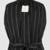 The long, fitted vest features a stand collar, a welt breast pocket, and pockets with pointed flaps.