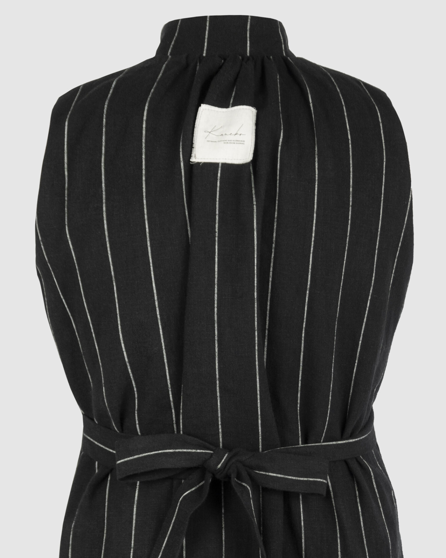 The long, fitted vest features a stand collar, a welt breast pocket, and pockets with pointed flaps.