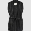 The long, fitted vest features a stand collar, a welt breast pocket, and pockets with pointed flaps.