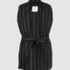 The long, fitted vest features a stand collar, a welt breast pocket, and pockets with pointed flaps.