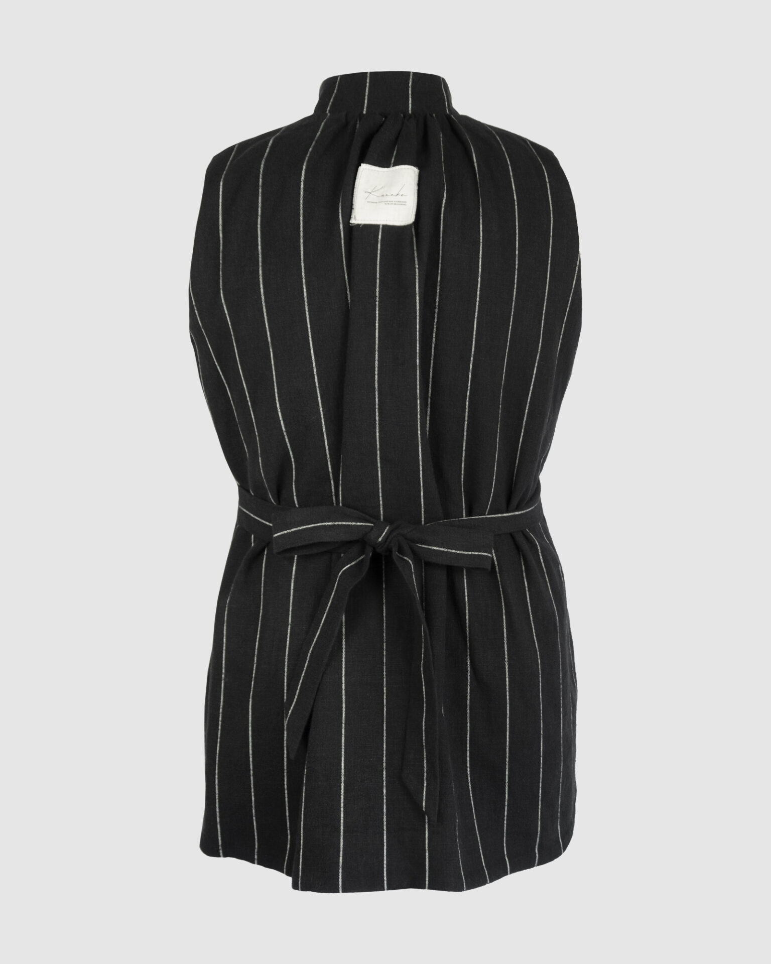 The long, fitted vest features a stand collar, a welt breast pocket, and pockets with pointed flaps.
