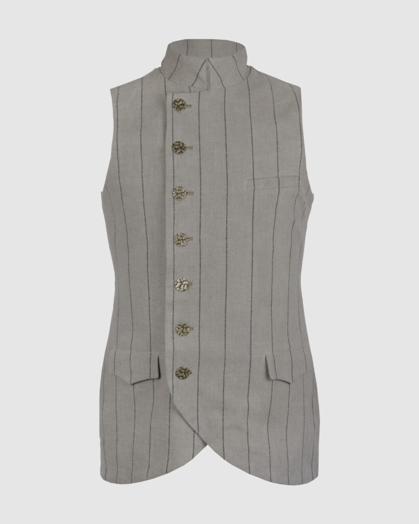 The long, fitted vest features a stand collar, a welt breast pocket, and pockets with pointed flaps.