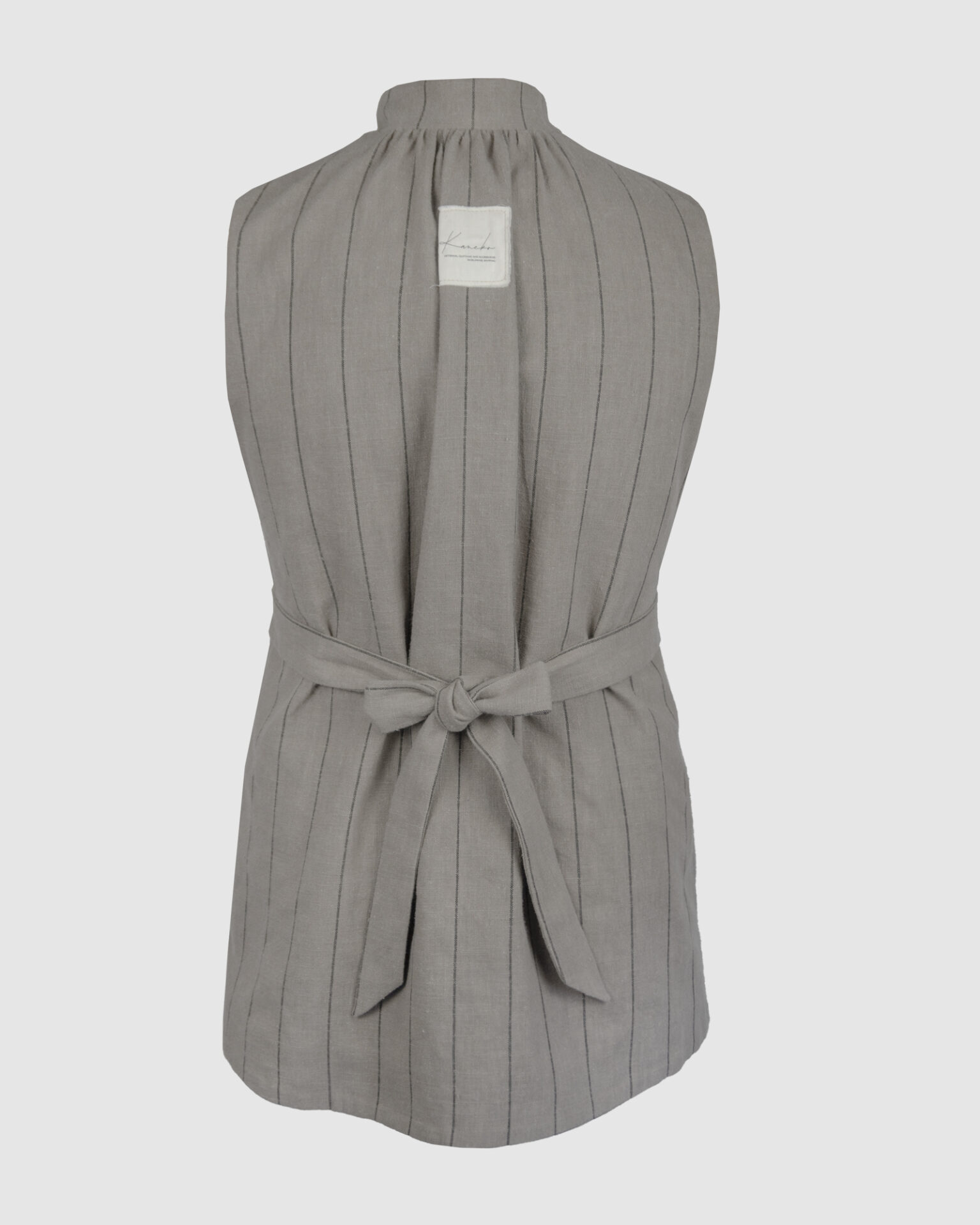 The long, fitted vest features a stand collar, a welt breast pocket, and pockets with pointed flaps.