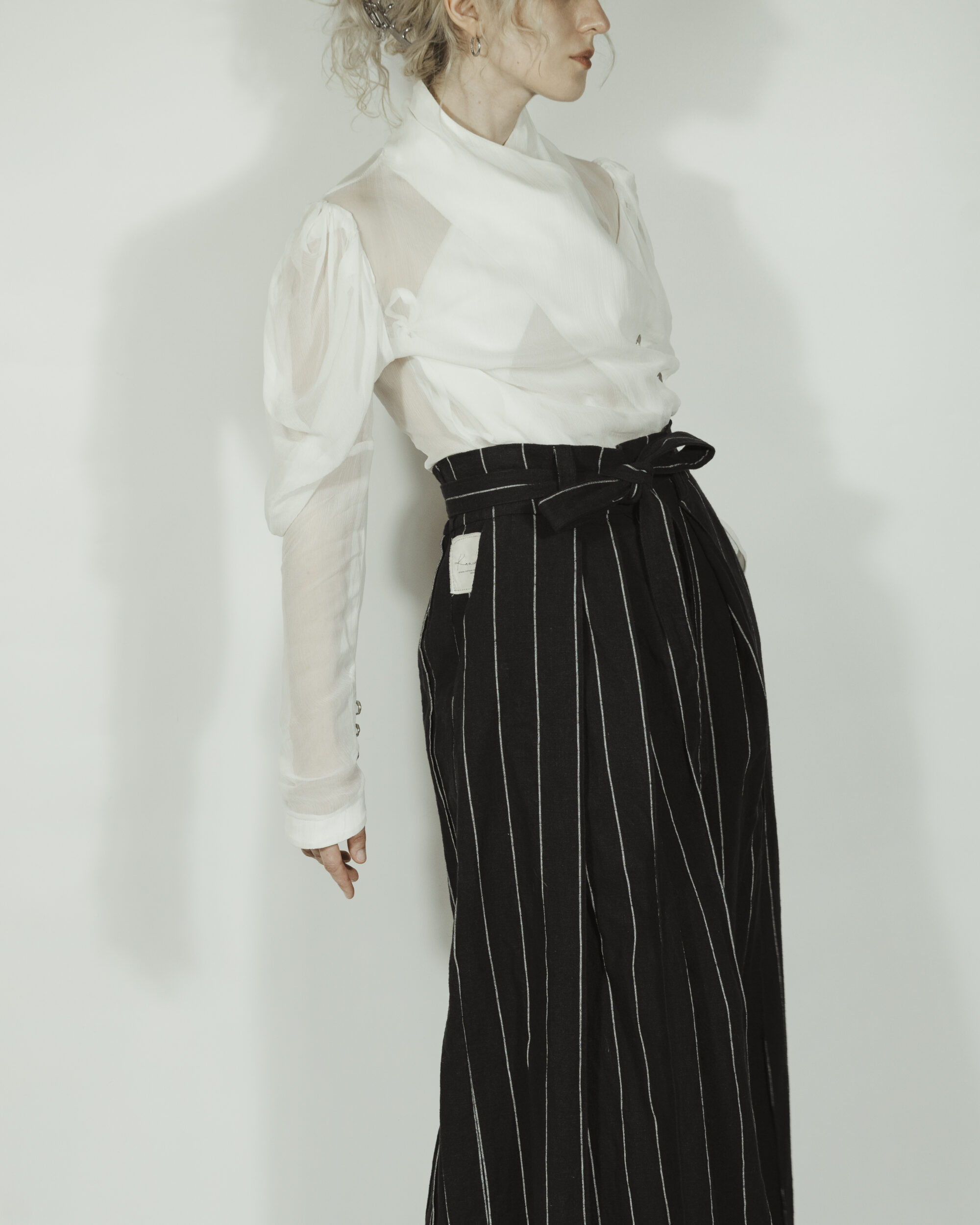 Fitted blouse with a draped front and voluminous sleeves The piece is inspired by traditional Japanese hakama trousers. It is a pair of wide-legged trousers with a high waistband.