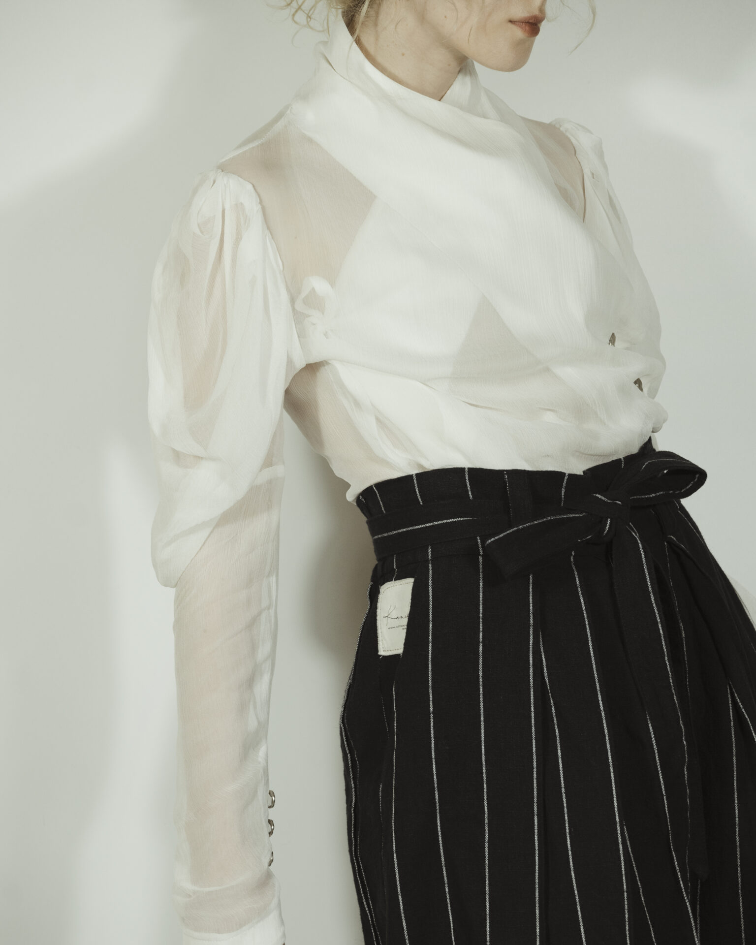 Fitted blouse with a draped front and voluminous sleeves The piece is inspired by traditional Japanese hakama trousers. It is a pair of wide-legged trousers with a high waistband.