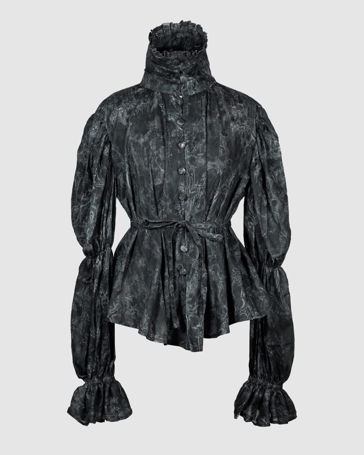 This loose-fitting blouse features a softly pointed front hem, a stand collar accented with a short ruffle, and a front button closure.